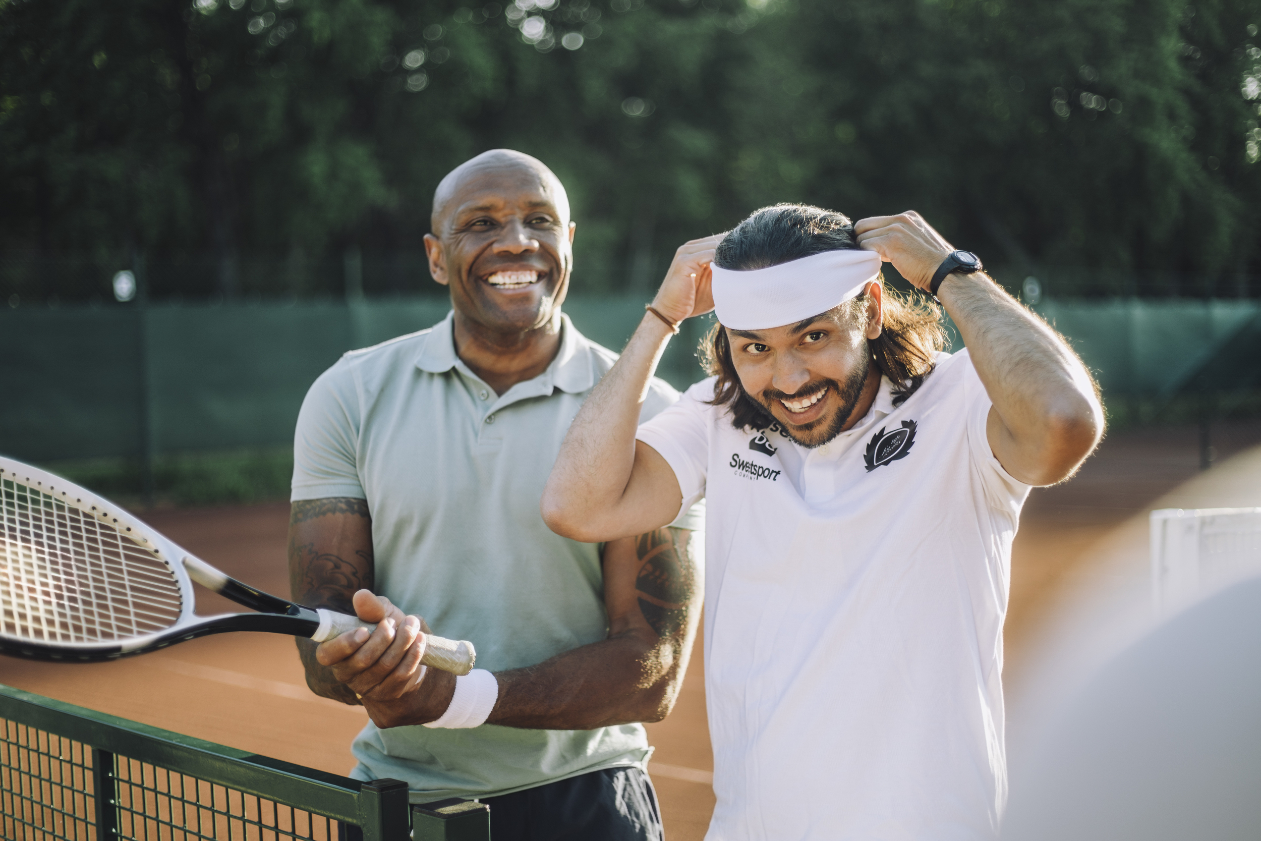 Glada vänner står på tennisbana och tittar bort